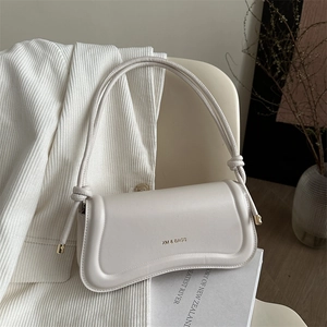 Minimalist beige leather shoulder bag with curved design and stylish knotted strap detail