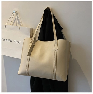Detail of beige faux leather tote bag with vertical stitching and minimalist tag decoration