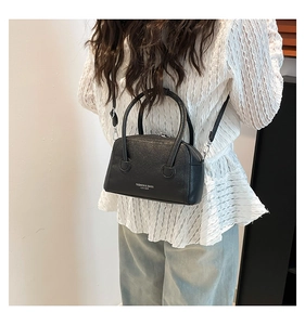 Detail of black pebbled leather handbag with white Fashion & Bags text on white clothing