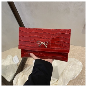 Close-up of red stone pattern PU leather clutch with golden metal bow decoration