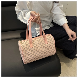 Dettaglio borsa Boston cilindrica rosa con motivo monogramma M nero e manici in pelle