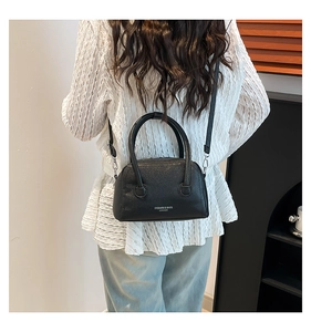 Detail of black lychee grain PU leather handbag with dual handles and crossbody strap