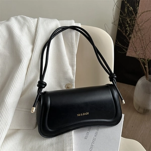 Minimalist black quilted shoulder bag with gold XM logo on white corduroy background
