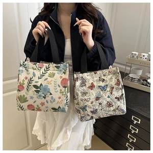 Detail of floral and butterfly embroidered canvas tote bags with black straps