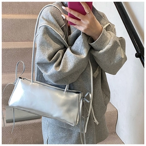 Detail view of silver metallic underarm bag featuring decorative side bow ribbons