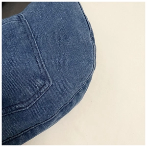 Detailed close-up of dark blue washed denim fabric with fine stitching and side pocket