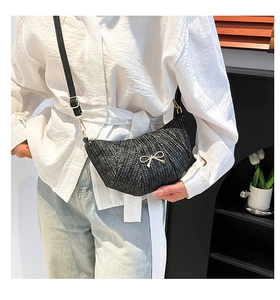 Detail of black woven crescent bag with gold butterfly accent shown on shoulder