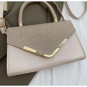Detail van roze handtas met glinsterende paillettenflap en goudkleurige metalen rand