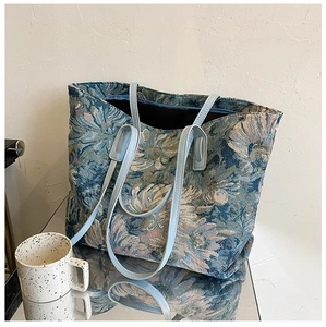 Detail of floral tapestry tote bag with light blue leather straps and spacious interior