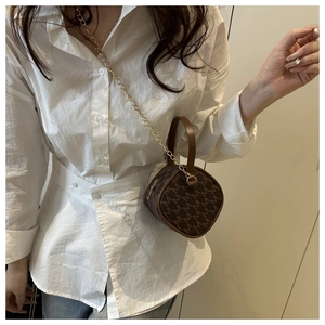 Close-up of mini brown monogram crossbody bag with gold chain strap worn by a model