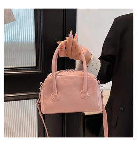 Detail of light pink lychee pattern PU leather handbag with zipper and adjustable strap