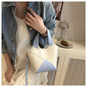 Détail d'un sac seau chic en cuir PU bicolore bleu clair et crème avec logo