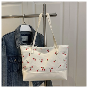 Detail of white corduroy tote bag featuring red cherry print and reinforced bottom base