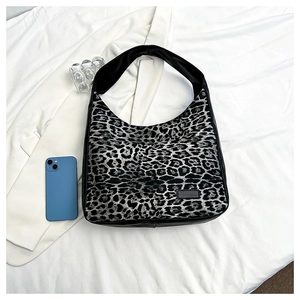 Gros plan d'un sac cabas léopard gris avec bordure en cuir noir sur fond texturé