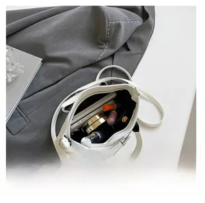 Vista dall'alto dell'interno della borsa a conchiglia bianca con cellulare e trucchi