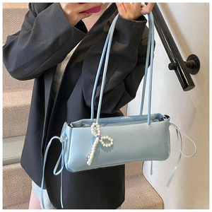 Detail of light blue underarm bag with white pearl bow and decorative side drawstrings