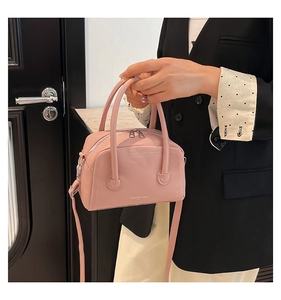 Détail du sac à main rose cerise en cuir texturé avec double zip et logo métal