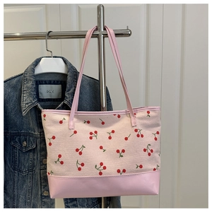 Detail of pink corduroy tote bag featuring red cherry prints and leather-like base
