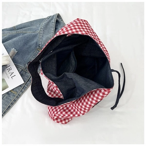 Detail of red checkered canvas tote bag with dark blue denim lining and side drawstrings