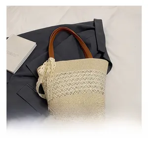 Detail of straw handbag with lace bow and leather handles on dark grey fabric