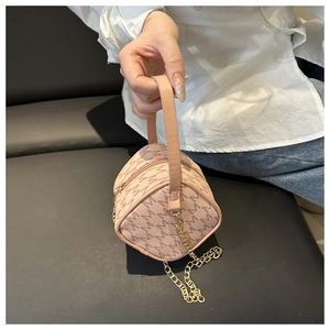 Detail of pink cylindrical mini bag with brown M-pattern and gold chain strap