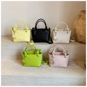 Mini PU tote bags in five colors with knotted handles and smiley charms on stone steps