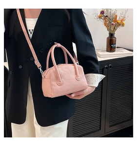 Détail de la texture cuir grainé rose sur sac carré avec des finitions en métal argenté