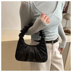 Dettaglio di una borsa a mano nera a pieghe abbinata a un top a coste azzurro chiaro