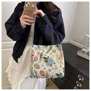 Detail view of jacquard floral tote bag with black woven handles and intricate patterns