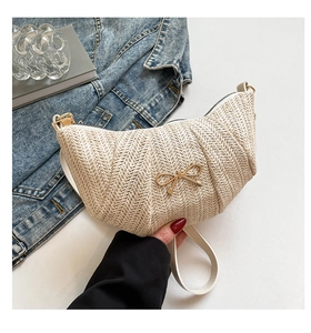 Close-up of woven cream hobo bag texture featuring a decorative gold bow buckle
