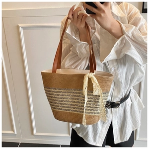 Close-up of woven straw tote bag featuring dark stripes and a cream lace bow detail