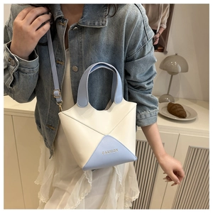 Sac seau bicolore blanc et bleu pour femme, porté avec une veste en jean.