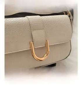 Detail view of cream crocodile pattern leather with gold U-shaped metal buckle