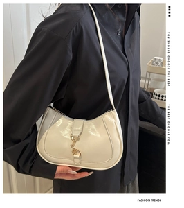 Gros plan d'un sac demi-lune blanc brillant avec boucle dorée et contraste de chemise noire