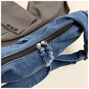 Detailed macro of dark denim bag zipper with stylish frayed tassels and metal hardware