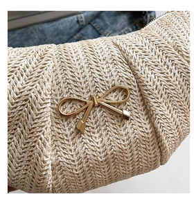 Macro view of beige herringbone woven texture and gold metal bow clasp on a handbag
