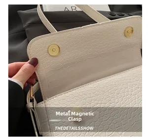 Close-up of hardware magnetic snap on white crocodile texture PU shoulder bag