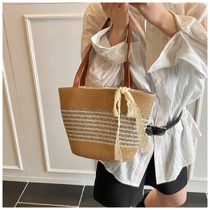 Detail of straw woven tote with leather handles and white lace ribbon on a summer bag