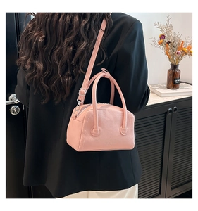 Close-up of pink lychee leather handbag worn with a black blazer for high contrast