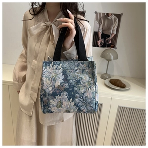 Detail of floral tapestry canvas tote bag featuring blue jacquard patterns and wide handles