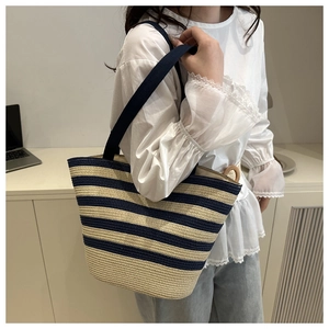 Detail of blue and beige striped straw tote bag with fabric shoulder strap for women