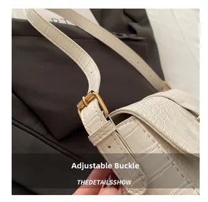 Detailed view of the adjustable golden metal buckle on a white crocodile embossed strap