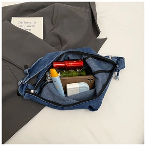 Detail of denim crossbody bag showing spacious interior with zipper and daily items