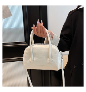 Close-up of white lychee pattern PU leather handbag with circular handles and shoulder strap