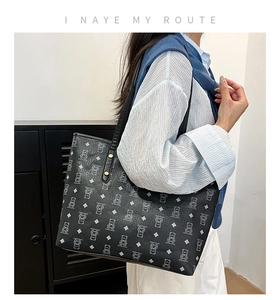 Close-up of black tote bag featuring cartoon bear print and lychee textured faux leather