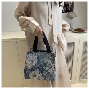Detail of vintage floral jacquard tote bag with stylish black strap and blue pattern