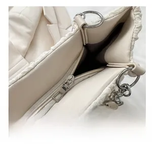 Detailed macro view of a smooth gold zipper on a plush cream textured shoulder tote bag