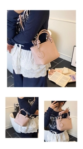 Detail of pink lychee grain faux leather handbag with knot handle and smiley charm