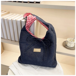 Detail of blue denim tote bag with red checkered lining and a decorative bow tie