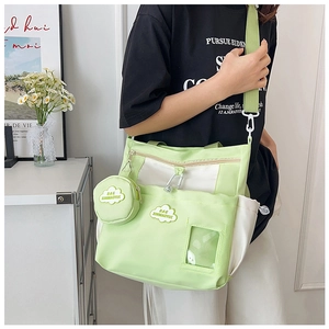 Détail du sac en toile vert clair avec breloque nuage, fente transparente et bandoulière large